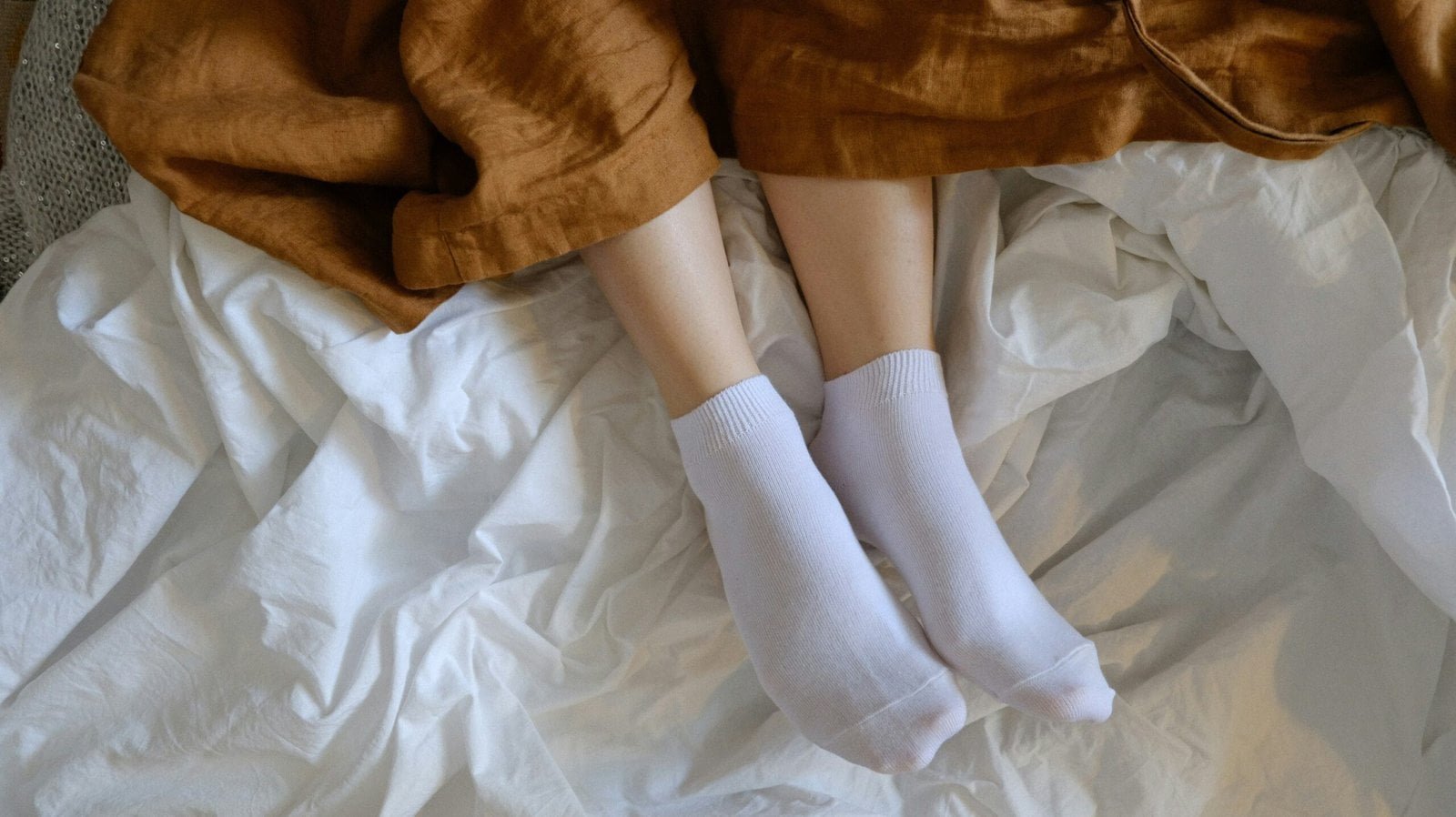 person wearing white socks on brown textile